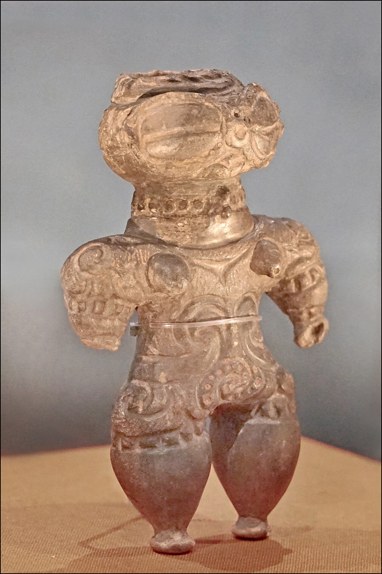 A Japanese dogu figurine has large eye forms and a patterned body.
