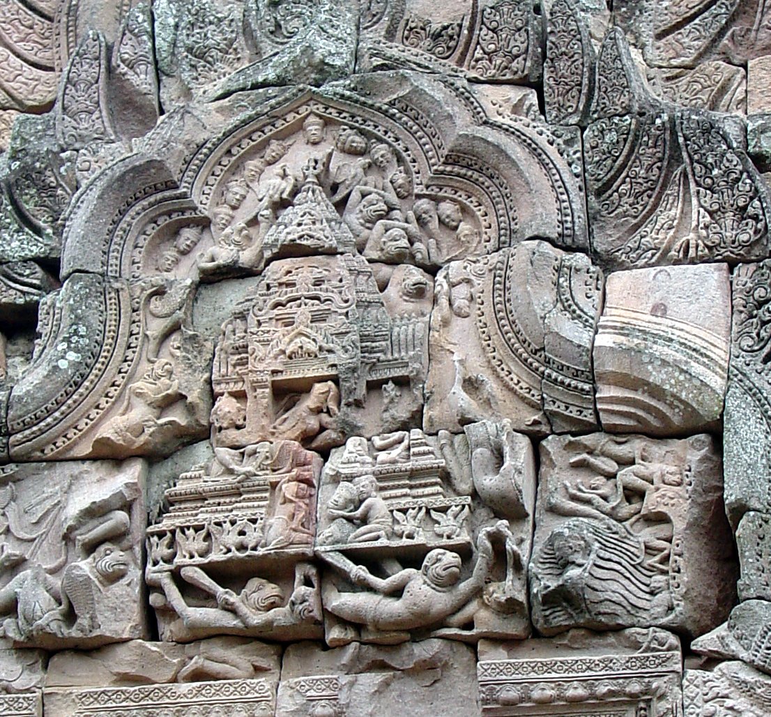 A carved temple scene contains a tiered architectural form surrounded by human and animal figures.