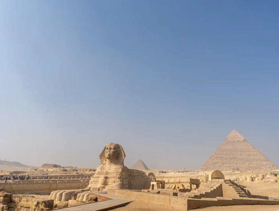 The Sphinx stands in the foreground with the pyramids of Giza behind it.