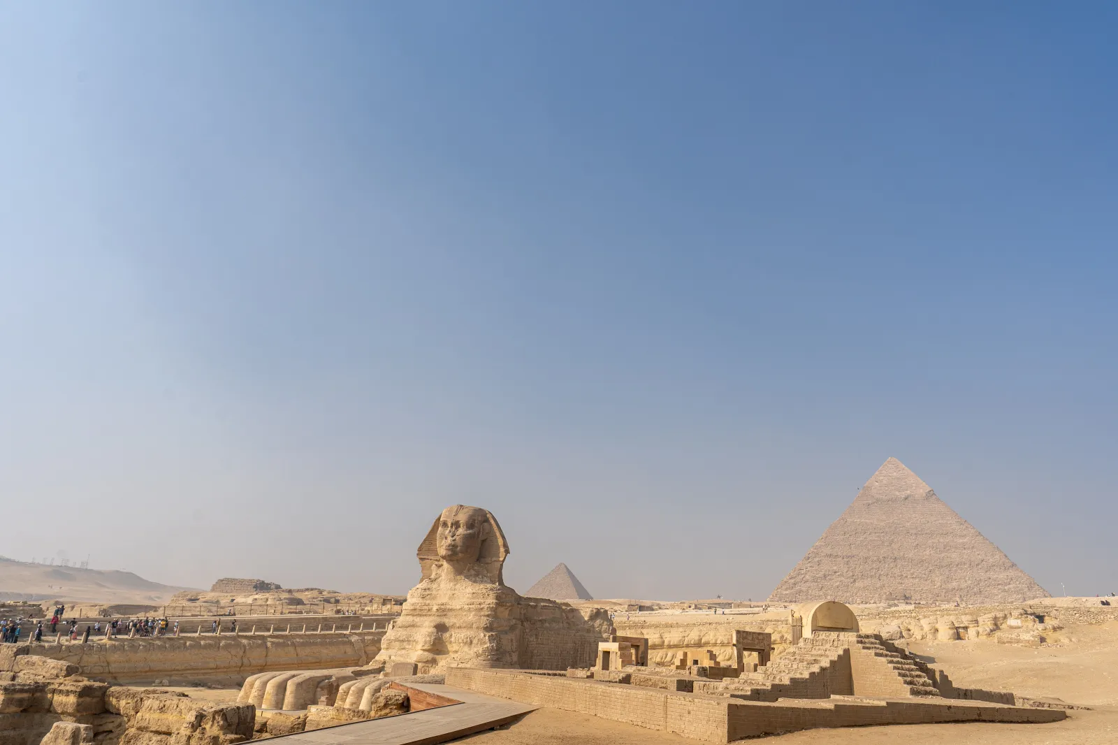 The Sphinx stands in the foreground with the pyramids of Giza behind it.